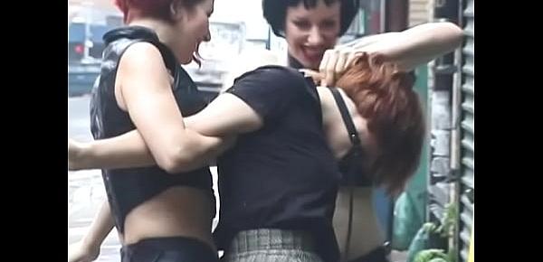  Two lustful lesbians tie their redhead girlfriend to a pole on the street and beat her with a whip